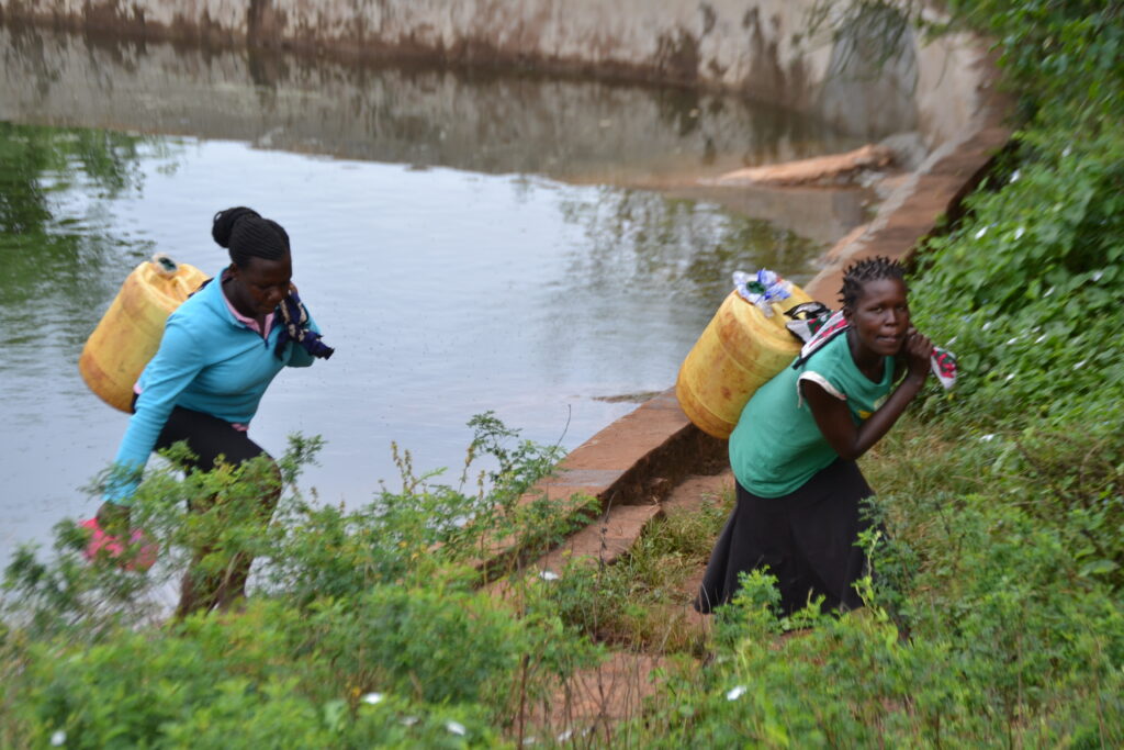 women collecting water from rock water catchment reservoir, Kenya